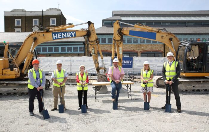6 people wearing protective clothing standing infront of the development site with machinery in the background